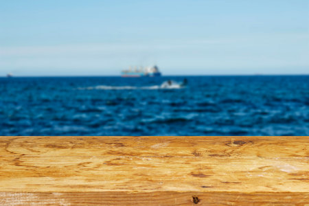 empty wooden table for mockup product display near a view of large container cargo and fishing boat...