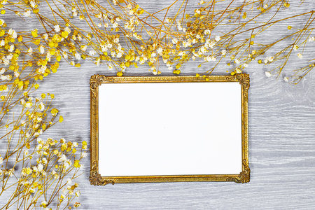 golden picture or photo frame mockup with pink baby's breath, gypsophila on gray wood tableの写真素材