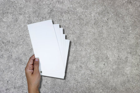 Hand holding white paper on cement floor background with copy space for add textの写真素材