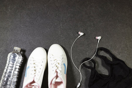 Healthy lifestyle, sport or athlete's equipment set : bottle of water with blue wireless headphone, sneakers on grunge gray backgroundの写真素材
