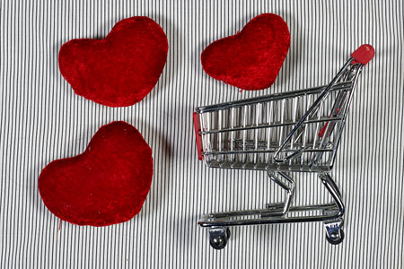 Shopping theme with shopping cart and three hearts shaped cushion on lines backgroundの写真素材