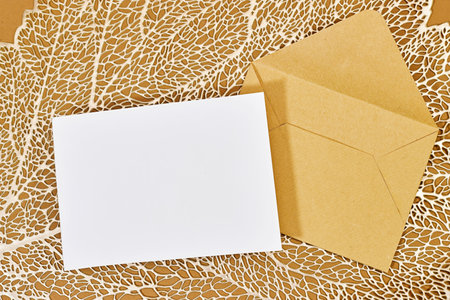 Blank greeting card, flyer or invitation card mockup and brown envelope with leaf plant, Valentines or women's day heart on brown backgroundの写真素材