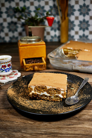 homemade tiramisu Italian dessert topped with coffee grinder, bean served on a black plateの写真素材