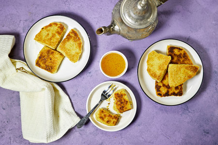 harcha or mbasses semolina algerian pancakes on an arabesque colorful plate above cutting board. Traditional algerian breakfast bread with honey bowlの写真素材