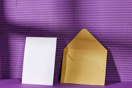 Blank greeting card, flyer or invitation card mockup and brown envelope with shadow, Valentines or women's day heart near purple wallの写真素材