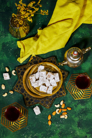traditional Turkish delight (lokum) with arabic tea and gypsophila vase on green grungeの写真素材