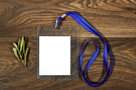 Blank badge mockup. Plain empty name tag mock up with olives leaves on wood table. Name tag with...