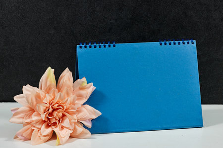 blue blank paper desk spiral calendar with dahlia flower on white tableの写真素材