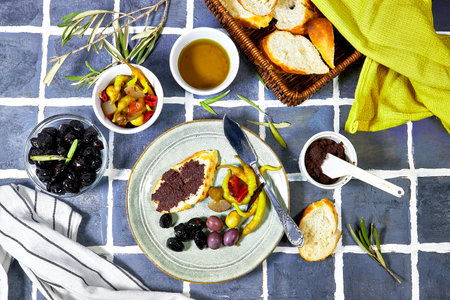 Tapenade - paste made from olives. Bowls with spreadable black and green olive cream and oil on tiles backgroundの写真素材