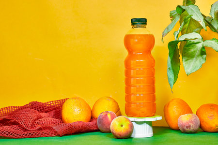 bottle of orange and peaches juices with flying fruitsの写真素材