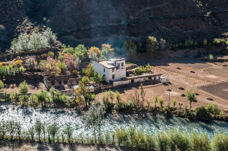 view of tibetan village near river and mountain in autumn, Sichuan,China.のeditorial素材