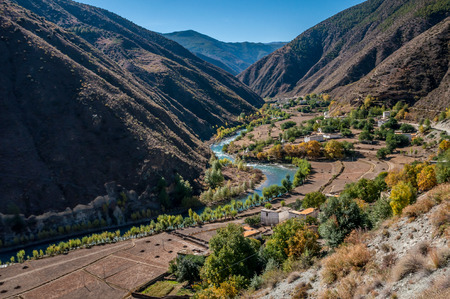 view of tibetan village near river and mountain in autumn, Sichuan,China.の写真素材