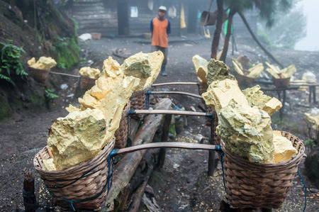 Kawah Ijen, Indonesia - April 24,2010 :  Worker and sulfur inside Ijen crater  in Ijen Volcano, Indonesia. He carries the load of around 60kg to the top of the rip and then 3km down.のeditorial素材