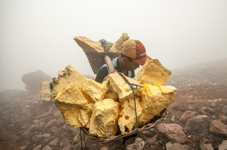 Kawah Ijen, Indonesia - April 24,2010 :  Worker carries sulfur inside Ijen crater  in Ijen Volcano, Indonesia. He carries the load of around 60kg to the top of the rip and then 3km down.のeditorial素材