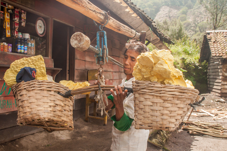 Kawah Ijen, Indonesia - April 24,2010 :  Worker weigh  sulfur inside Ijen crater  in Ijen Volcano, Indonesia. He carries the load of around 60kg to the top of the rip and then 3km down.のeditorial素材