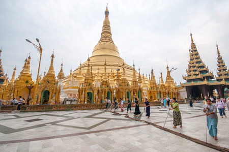Yangon, Myanmar - March 14, 2011: Row of Myanmar women cleaning floor of  Shwedagon Pagoda before sunset in Yangon of Myanmar. It is the most sacred Buddhist pagoda for the Burmese with relics of the past four Buddhas enshrined within.のeditorial素材