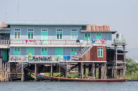 Inle, Myanmar - March 21,2011:  Traditional stilts wooden house and boat of Intha people in water on Inle lake, Myanmar (Burma). The people of Inle Lake live in four cities bordering the lake.のeditorial素材