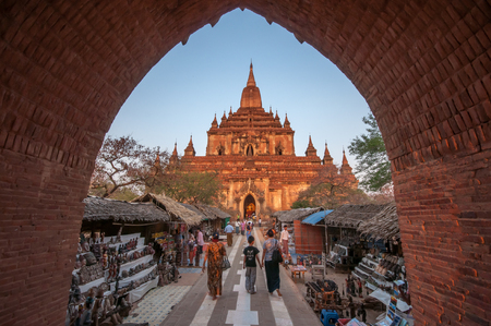 Bagan,Myanmar-March 19,2011 : Htilominlo Temple entrance with tourist passing by street market to enter the temple in Bagan, Myanmar.This large temple was built by King Nantaungmya in 1218. Situated close to the road between Nyaung U and Bagan.のeditorial素材