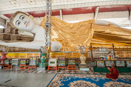 Bago,Myanmar-March 23,2011: The Myanmar monk praying at Shwethalyaung reclining buddha, Bago, Myanmar,The image has a length of 55 meter and a height of 16 mete ,Built by the Mon in 994 during the reign of Mon King Migadepa.のeditorial素材