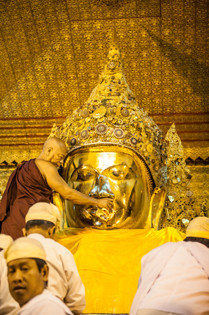 MandalayMyanmarMarch 172011 : Myanmar senior monk washing Mahamuni Buddha image  wash every morning at 4am. in Mandalay Myanmar .Mahamuni is the oldest Buddha statue in Myanmar It is also known as the Maha Myat Muni or Phaya Gyi.のeditorial素材