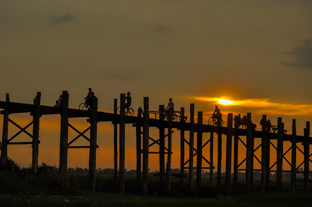 Mandalay,Myanmar-March 16,2011 : Unidentified Myanmar  People with bicycle on U-Bein bridge in sunset in Mandalay, Myanmar. The U-Bein bridge is the longest teak bridge in the world, 1.2km lenght is spanning the Taungthaman Lake. It is 200 years old.のeditorial素材