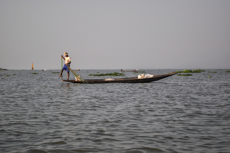 Inle, Myanmar - March 21,2011: Inle  fisherman on boat catching fish by traditional net with possess the leg-rowing style in Inle of Shan state in Myanmar.Inle lake is 22km long and about 11km wide. The lake is at 1328 metres above sea level and  full of のeditorial素材