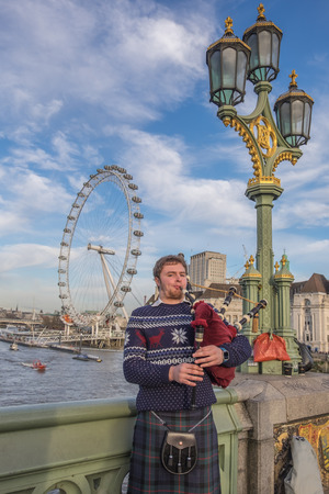 London, UK - December 22, 2016 : Unidentified bagpiper Scottish clothes playing bagpipes at Westminster Bridge in London, England.のeditorial素材