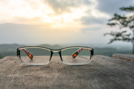 Eyeglasses on wooden table and sunrise backgroundの写真素材