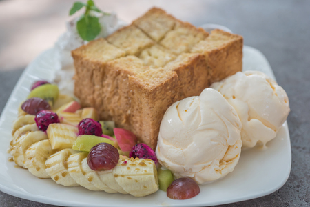 Mixed fruit and Honey toast with Ice cream in white dish on tableの写真素材