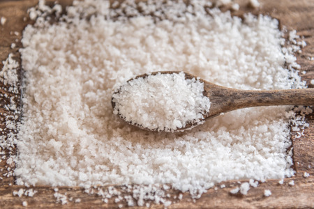 White salt, on a wooden bowl with a wooden spoon.の写真素材