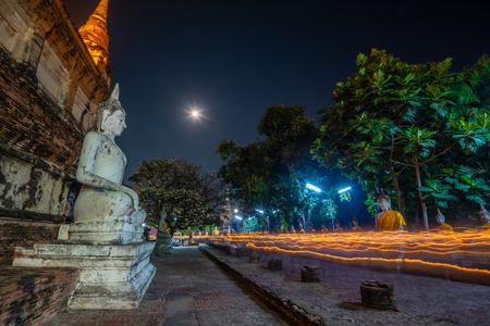 Buddhists people walking (motion blur)  with lighted candles in hand around a ancient temple on Magha Puja day at Ayutthaya province of Thailand.の写真素材