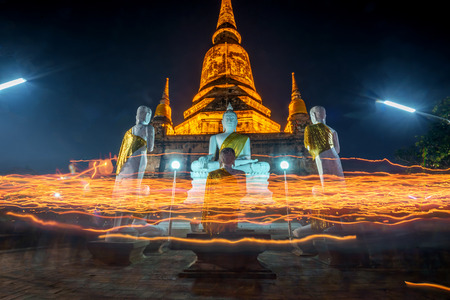Buddhists people walking (motion blur)  with lighted candles in hand around a ancient temple on Magha Puja day at Ayutthaya province of Thailand.の写真素材
