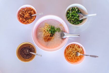 Rice porridge or congee is favorite Asian breakfast with sliced ginger ,pepper,spring onion and  fried garlicの写真素材