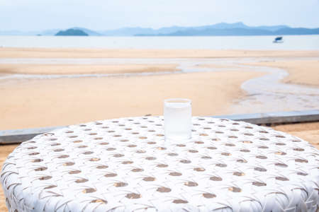 A glass of drinking water on white table next to the beach restaurantの写真素材
