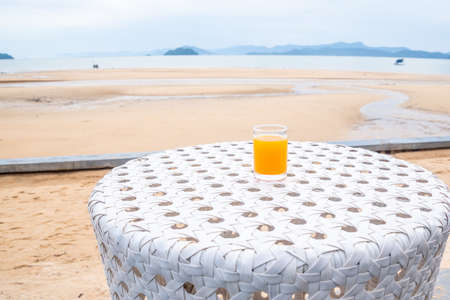 A glass of orange juice on white table next to the beach restaurantの写真素材
