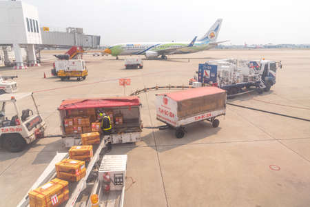 Bangkok, Thailand- January 24 2021 : Airline crew loads checked baggage into airplane cargo and refueling of the aircraft at Don Mueang airport (DMK) in Bangkok ,Thailand.のeditorial素材