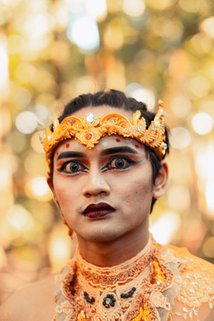 Asian men wearing black eyeshadow and red black lips on her face while wearing a gold crown on the head inside the villageの写真素材
