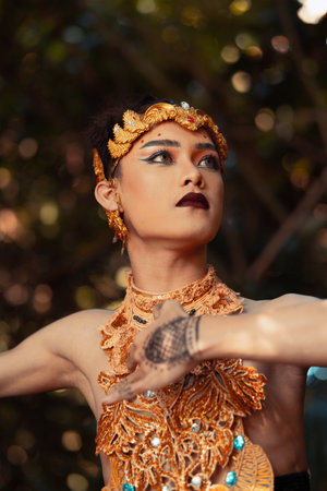 A Traditional dancer with golden clothes and a golden crown posing bravely in the jungle during the daylightの写真素材