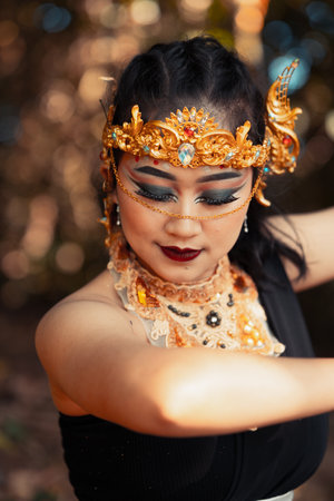 Indian woman with black clothes dancing pose while in makeup and gold jewelry on her body inside the forestの写真素材