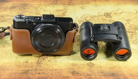 old vintage pocket camera and binocular on a old world map