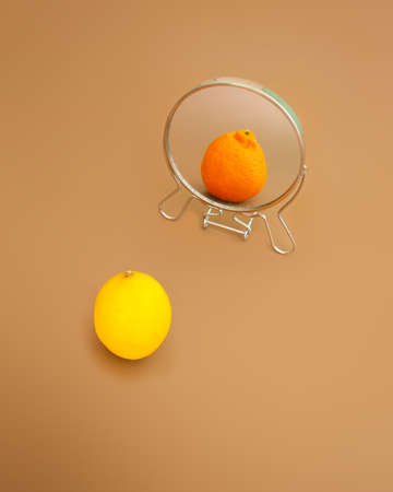 Summer background with mirror reflection of fresh lemon as orange. Surrealistic picture abstract vision.の写真素材