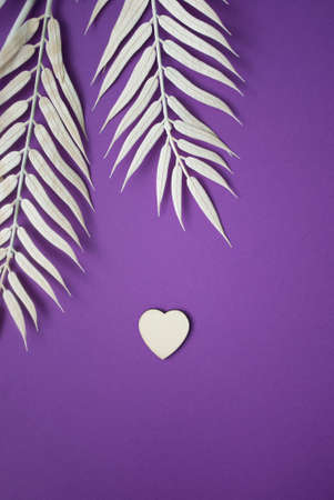 Heart on violet background with palm leaf. Creative composition. Valentines day concept. Flat lay.の写真素材