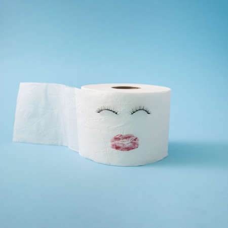 Cute female toilet paper roll with eyelashes and red lipstick isolated on pastel blue background. Side view, interesting concept.の写真素材