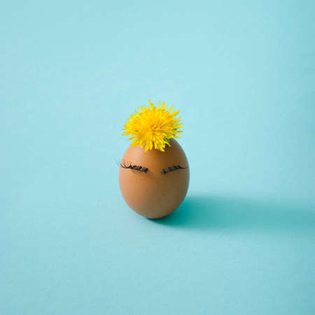 One spring girl egg with yellow flower and eyelashes  Side view, interesting concept.の写真素材