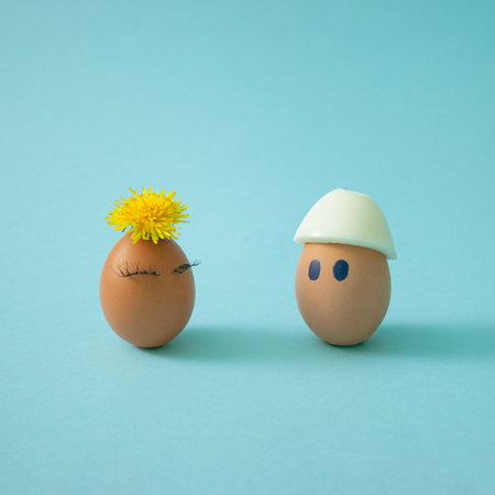 Two Ester eggs, one girl egg with yellow flower and eyelashes and one boy egg with white hat, a creative love idea. Side view, interesting concept.の写真素材