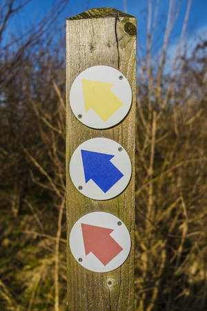 three coloured arrows giving directions on wood post