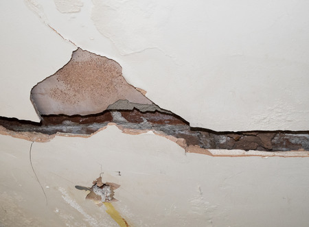 badly cracked plasterboard on interior wall showing bricks behindの写真素材