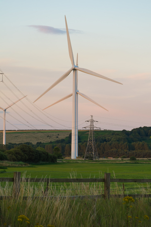wind turbines and electricity pylons in a grass fieldの写真素材
