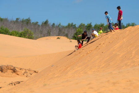 MUI NE, VIETNAM - DECEMBER 25, 2015: Children ride on the Red dunes. The Surroundingsのeditorial素材