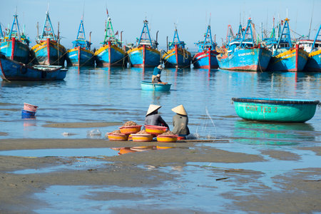 MUI NE, VIETNAM - DECEMBER 25, 2015: YALTA, UKRAINE - JUNE 09, 2013: Two women sit with their catch amid the fishing boats. Fish haven in Mui Neのeditorial素材
